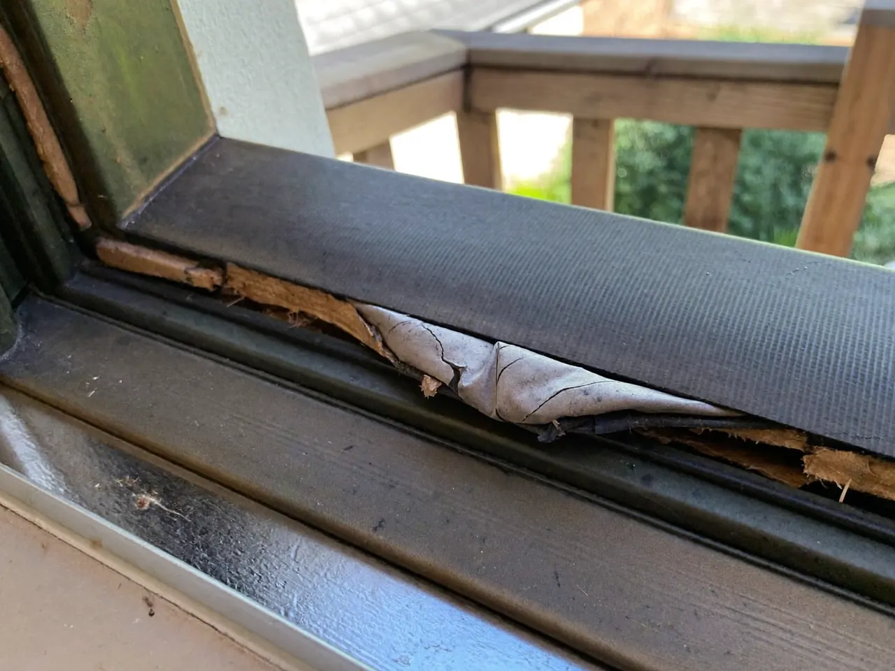 A hand checking for a draught along the rubber seal of a closed window